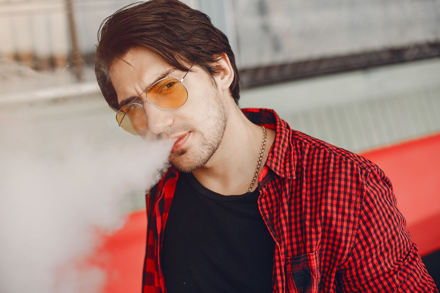 Close-up of man holding disposable vapes near Renaissance with a handheld device.