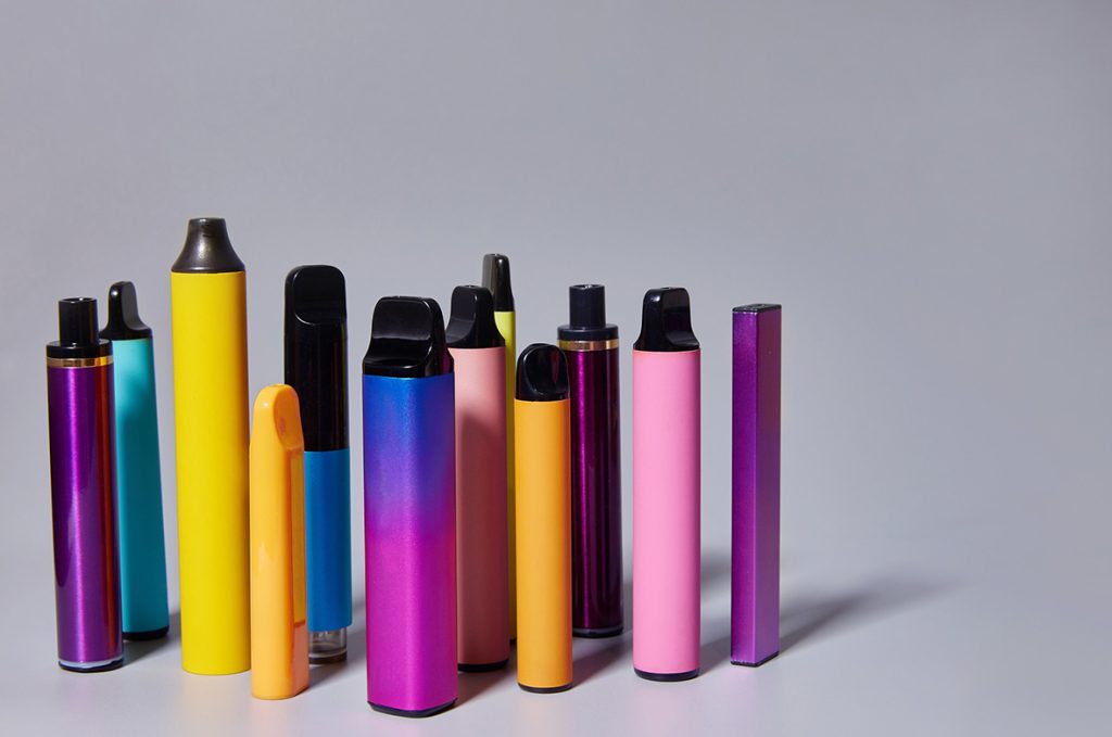 A selection of colorful, bright disposable vapes Tulsa lined up against a light grey studio background for a blog.