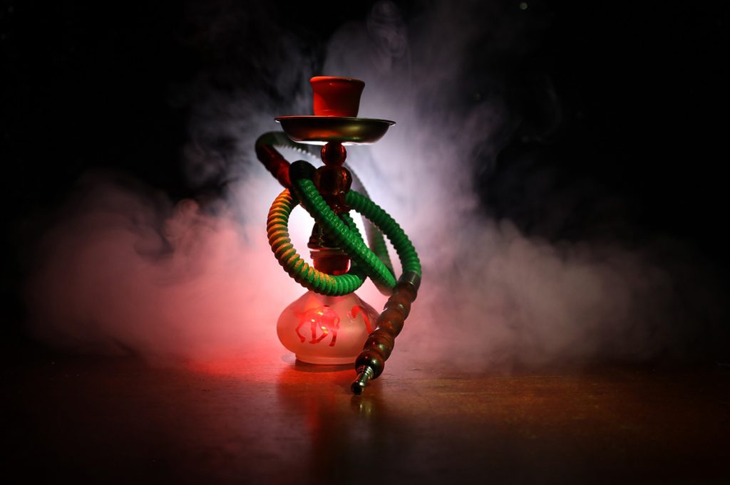 Hookah with red glow and green hose in a cloud of smoke, perfect setup from the best shisha store Tulsa.