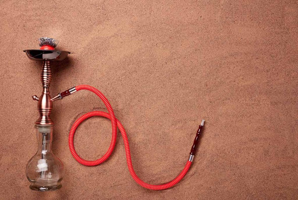 Elegant copper and clear glass hookah with red hose, photographed from above for the shisha store Tulsa blog.