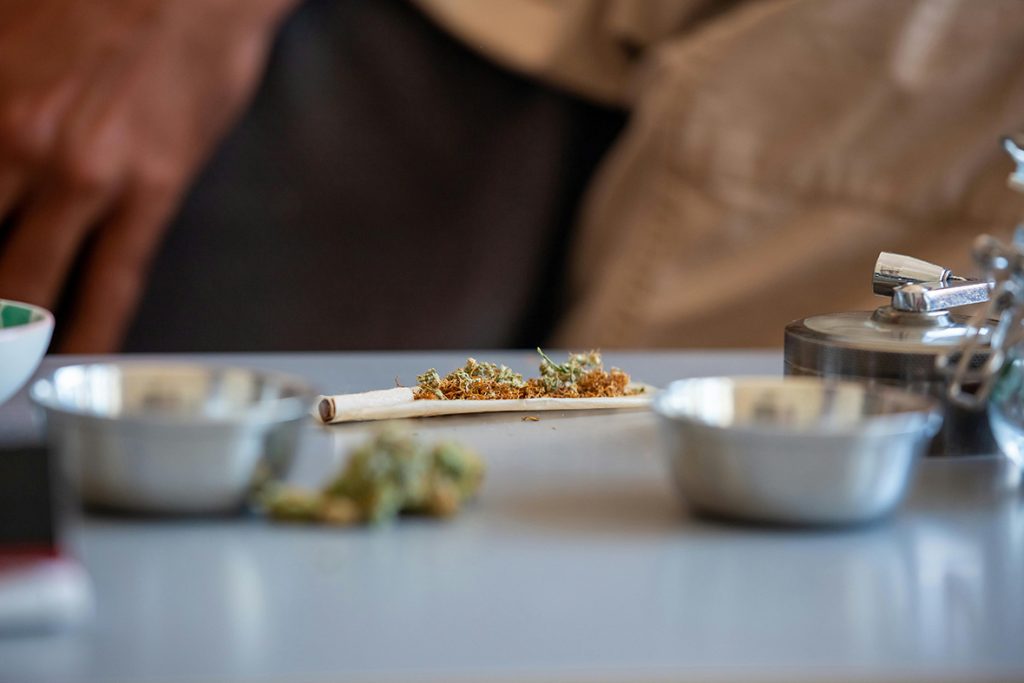 Dried herb on open rolling papers Tulsa with filter, next to a grinder for a premium blog.
