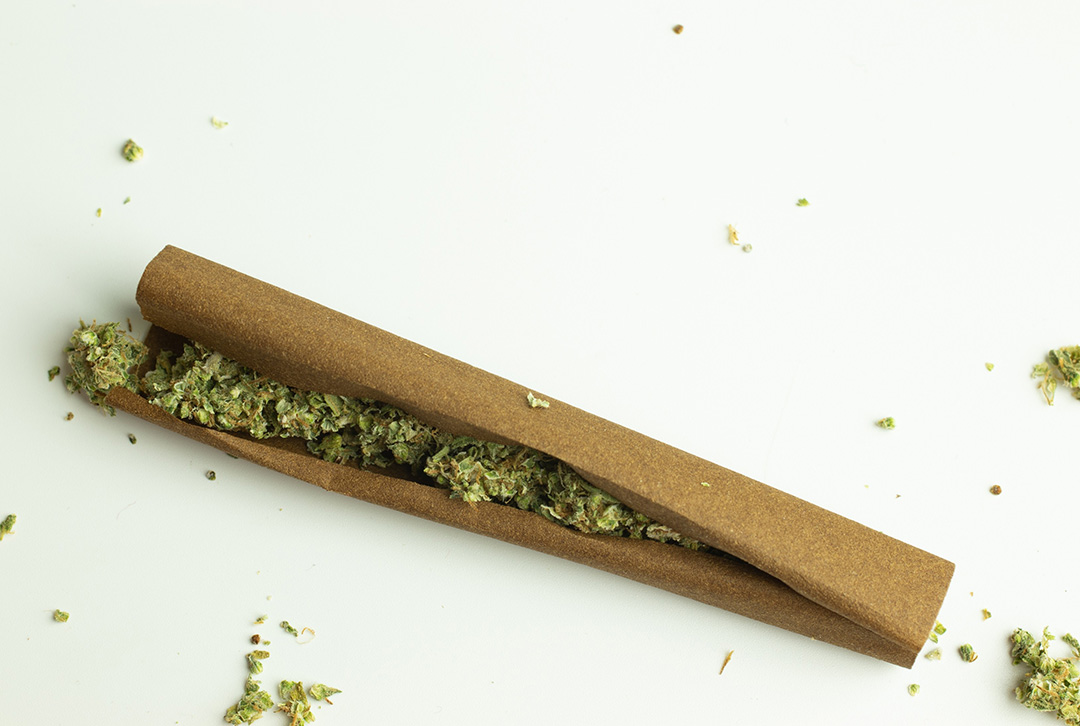 A loose brown cigar wrap filled with ground dry herbs on a bright white surface. Shop rolling papers Tulsa for quality.
