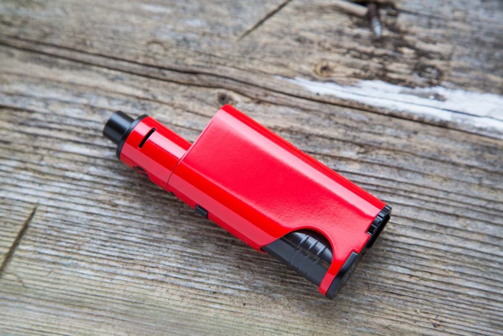 Bright red box-style vaporizer with black details on a rustic wooden surface, not a disposable vapes Tulsa.