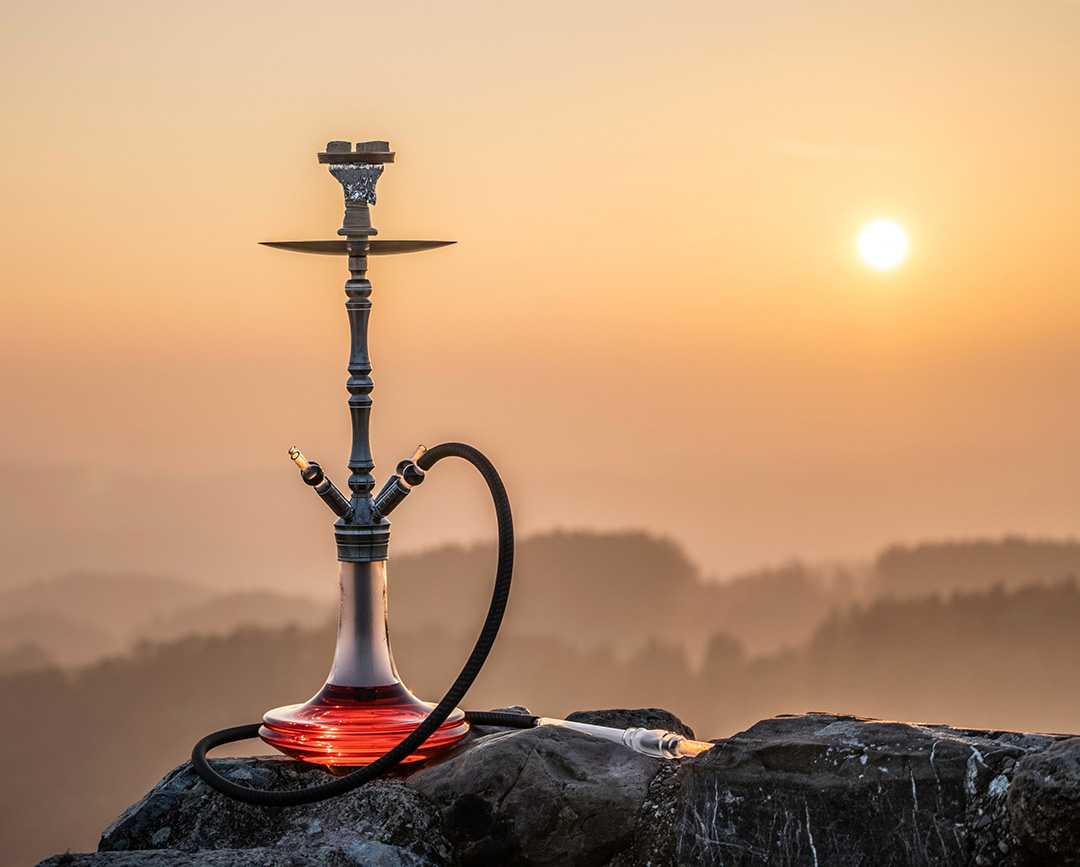 Modern hookah set up outside on a rock overlooking a foggy mountain sunset, available at shisha store Tulsa.