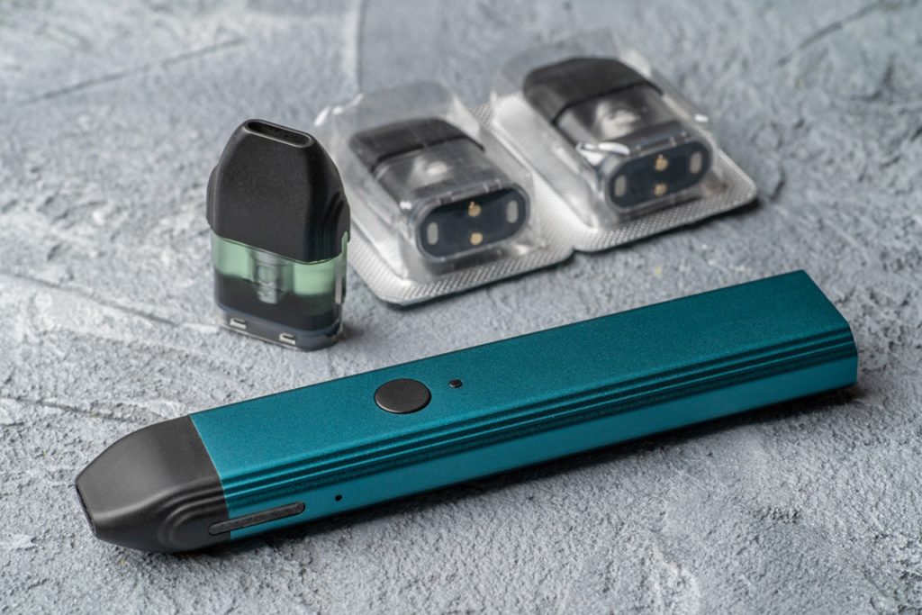 Teal pod vape system displayed with replacement nicotine pods and packaged refills available in Tulsa smoke shops