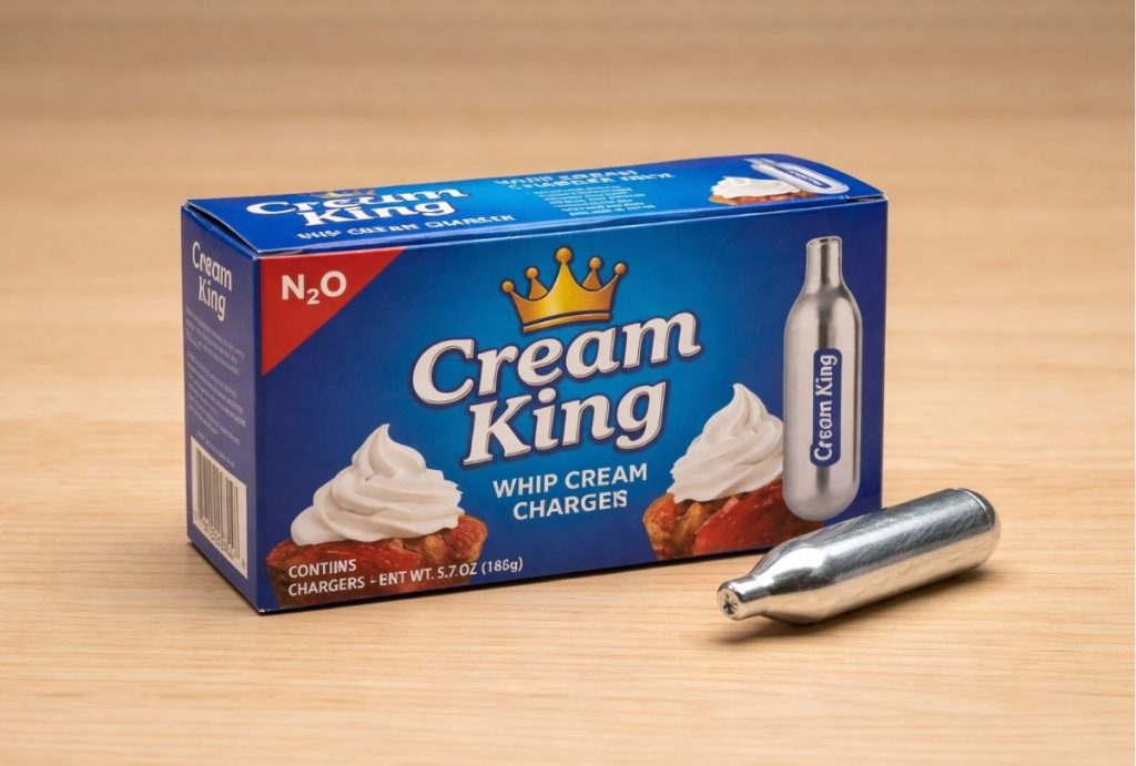 Cream King brand whip cream chargers in a blue box with one silver N2O cartridge on a wooden table. Available in Tulsa.