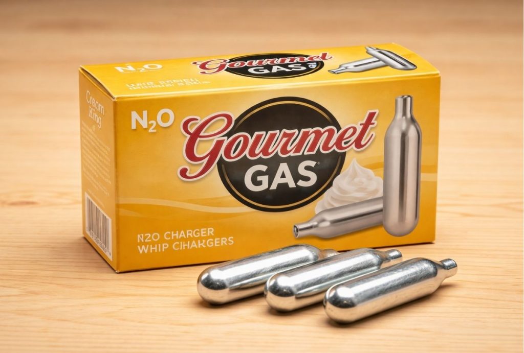 Box of Gourmet Gas N2O whip cream chargers with three silver cartridges on a wooden table. Shop whip cream chargers Tulsa.