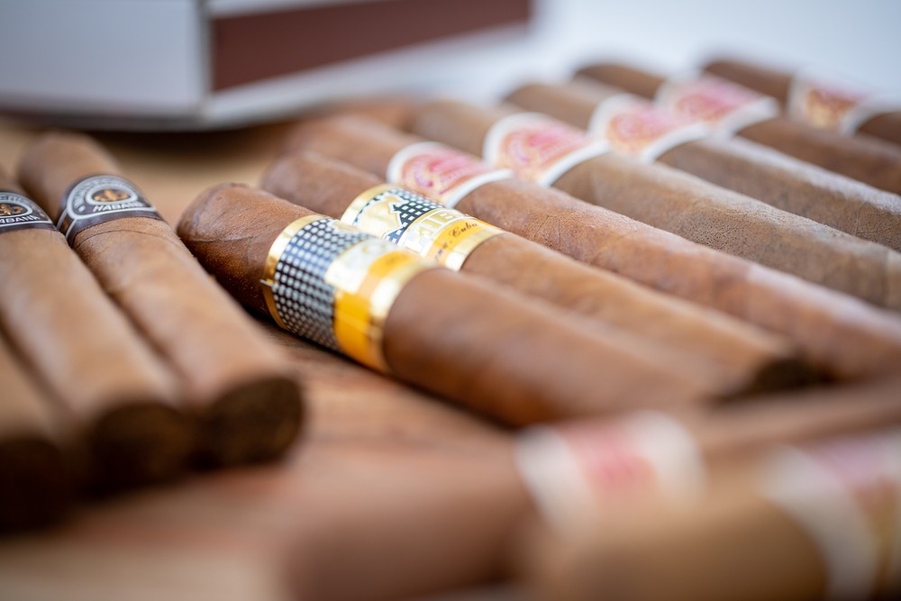 A close-up view of several premium cigars with distinct bands lying on a wooden table, showcasing choices in a cigar shop tulsa.