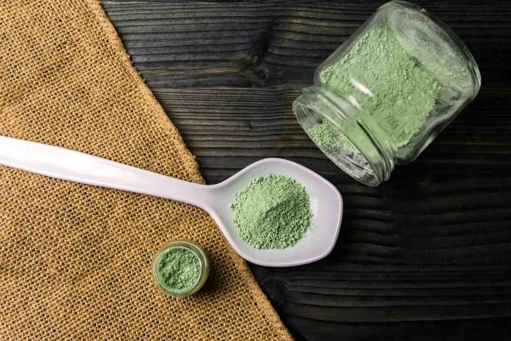 Bulk green powder in a glass jar and spoon at a kratom shop Tulsa residents trust for fresh herbal products.