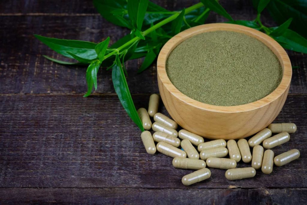 Premium kratom powder and capsules for kratom retail Tulsa markets, featuring fresh green leaves on a dark wood background. 