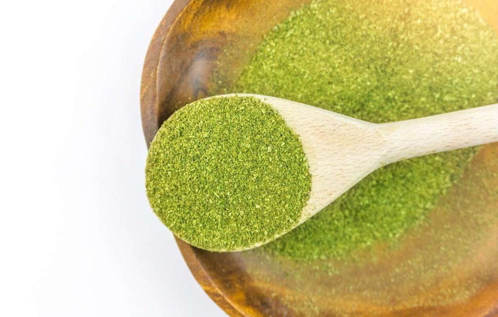 A wooden spoon filled with premium green vein powder from a top-rated kratom shop Tulsa locals visit for quality.