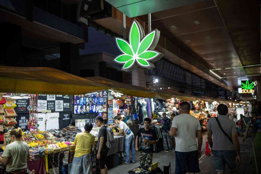 Glowing cannabis leaf sign hanging over a busy night market near a popular smoke shop Tulsa.