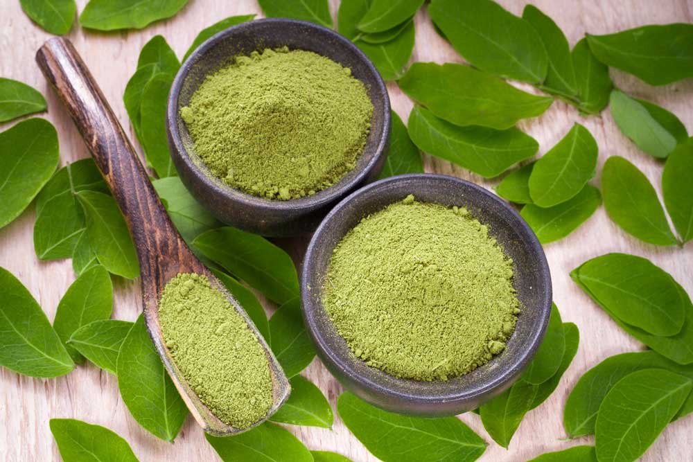 Finely ground green herbal powder in wooden bowls from a premier kratom shop Tulsa OK blog guide for consumers.