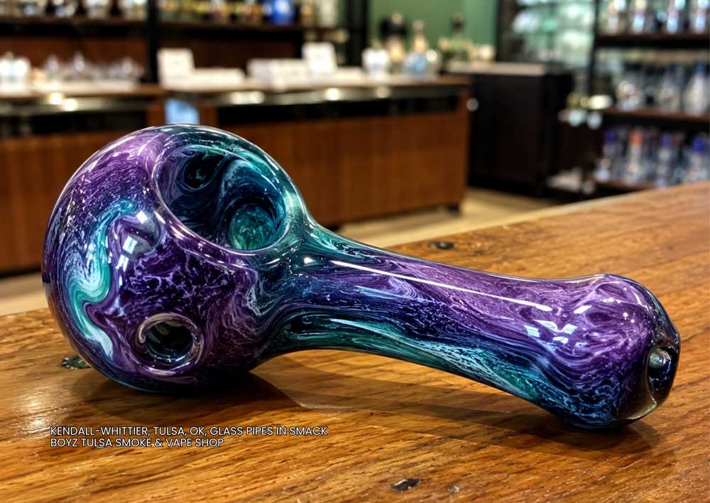 Swirling purple and teal hand-blown pipe displayed on a counter, part of the premium glass pipes Tulsa collection.
