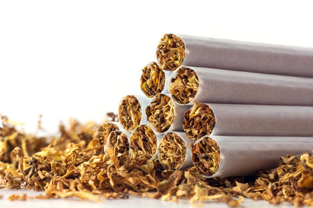Stack of cigarettes with loose tobacco at a cigarette shop Tulsa, showcasing quality tobacco products for sale.