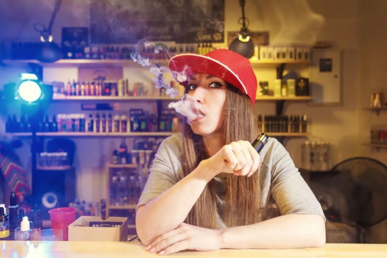 Woman vaping in a vibrant vape shop in Tulsa, surrounded by e-liquids and devices.