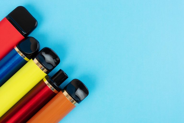 Close-up of five vibrant disposable vapes Tulsa with black tips, angled across a solid blue background.