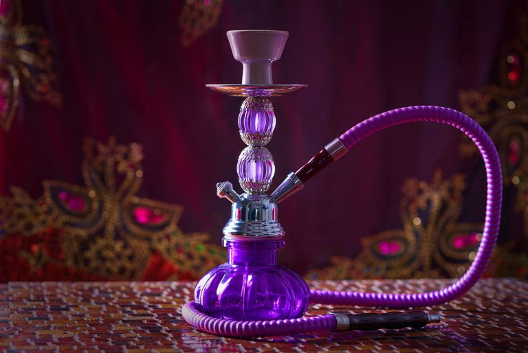 Stunning purple glass hookah on a patterned tablecloth, an eye-catching piece from our shisha store Tulsa.