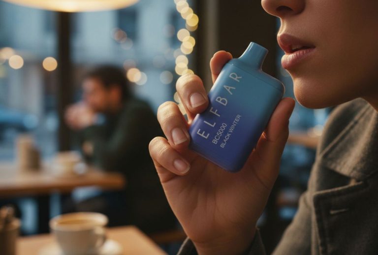 A person holds the blue Black Winter Elf Bar BC5000 in a cozy cafe setting, demonstrating popular disposable vapes Tulsa has.